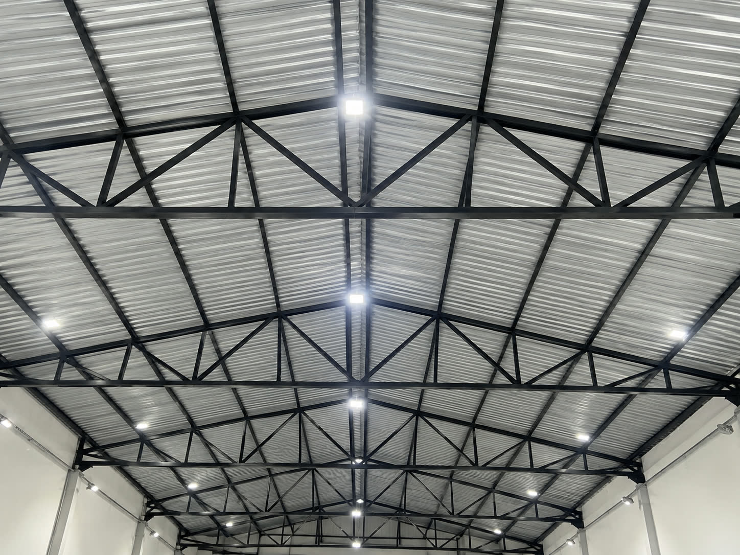 Vista interna de cobertura com estrutura metálica treliçada e telhamento instalado